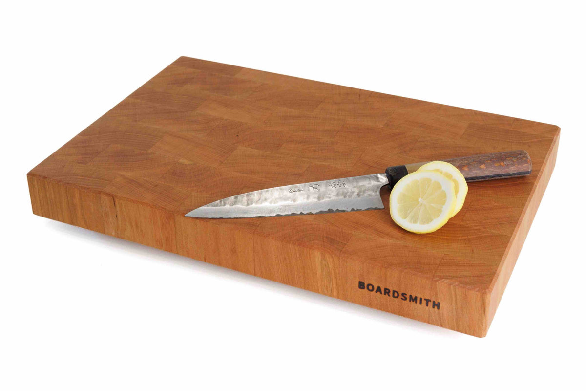 Cherry end grain cutting board by The Boardsmith with chef knife and sliced lemon on top