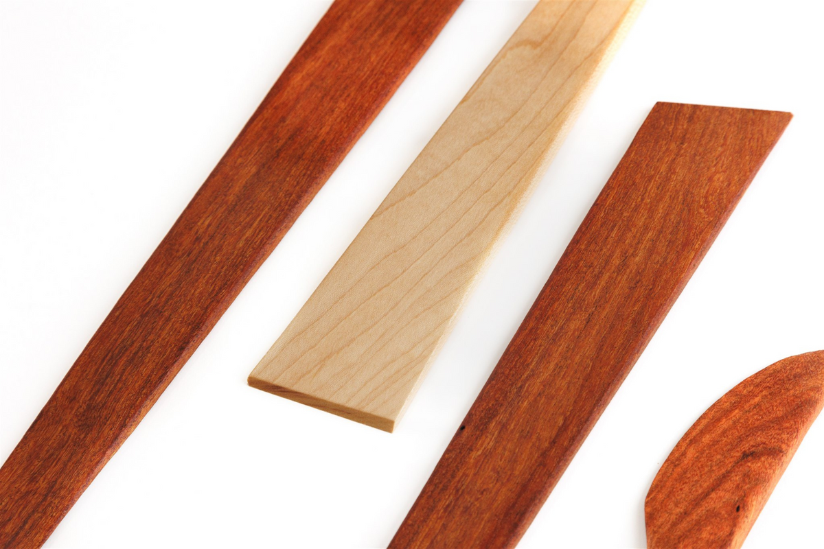 Angled close-up of 4-piece wooden utensil set with maple and mesquite tools on white background